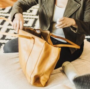 Best Work Bags for Women woman organizing a leather tote bag for work